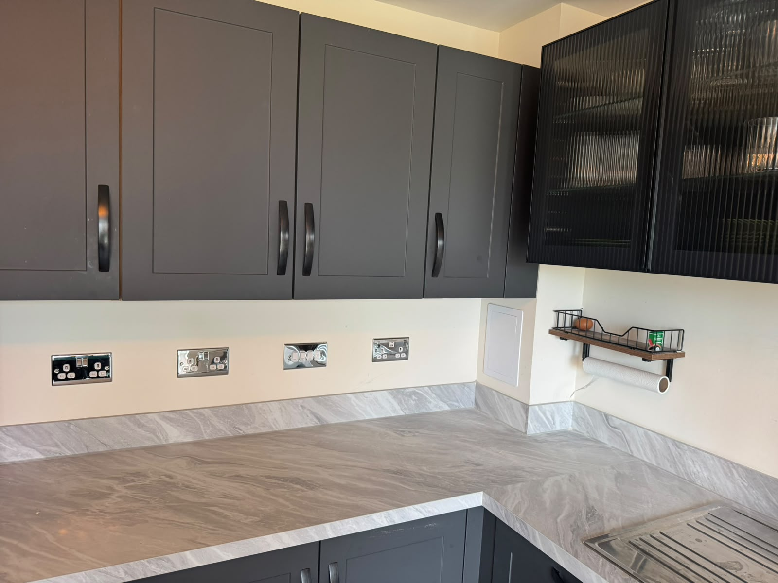 Chrome sockets neatly installed along a kitchen worktop with dark units
